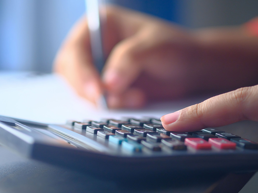 Person working through figures with a calculator and pen
