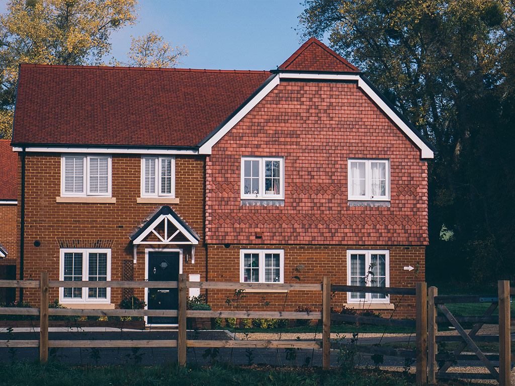 Red-brick detached house with a wooden fence
