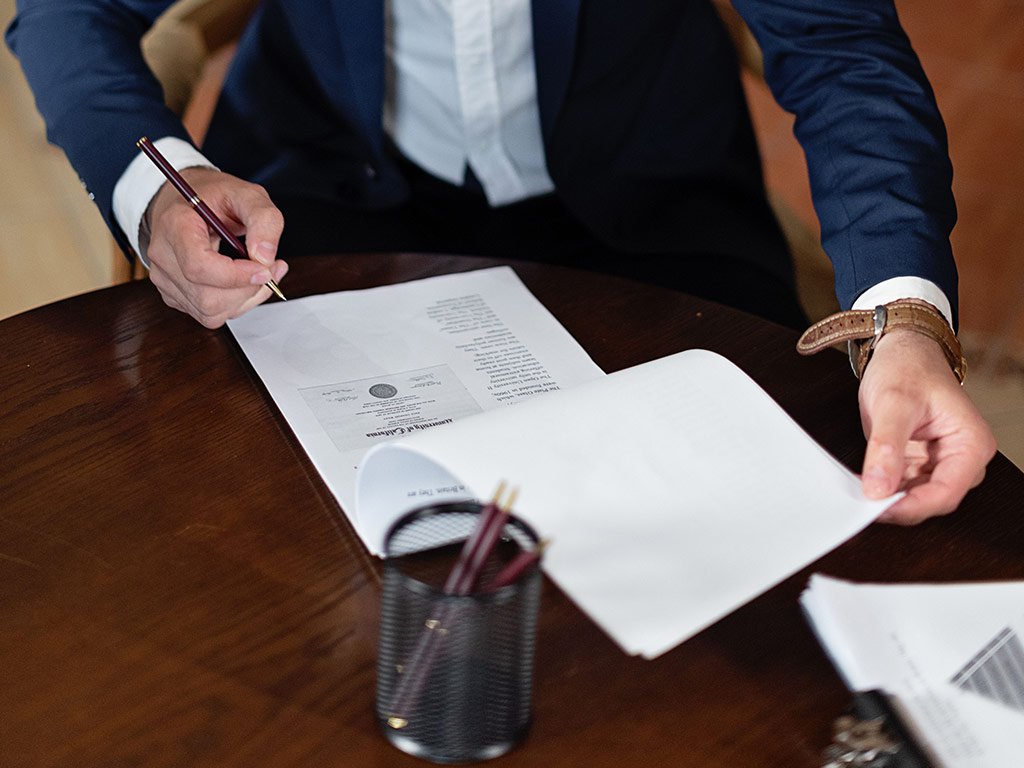 Person reviewing and signing a contract at a desk