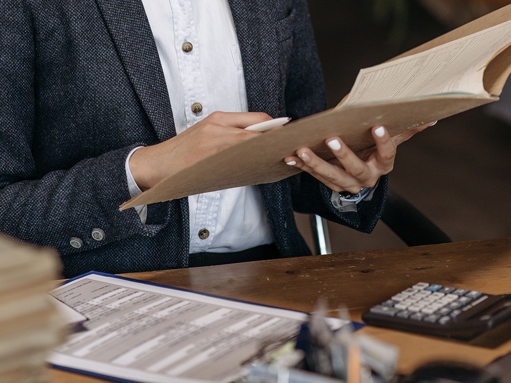Person checking documents in a folder at a desk